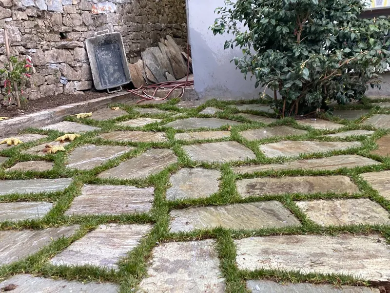 Green slate πλακόστρωτο αίθριο αρμοί με γρασίδι τοίχος αντιστήριξης — PelionStones.gr