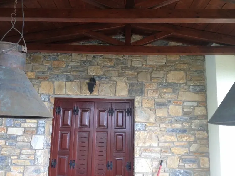 Ochre rust stone cladding ξύλινη πόρτα φανάρι βεράντας — PelionStones.gr