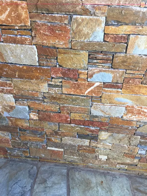 Ochre rust επένδυση τοίχου πάνω από γκρι πλάκες — PelionStones.gr